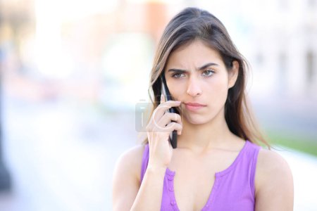 Photo for Suspicious woman attending phone call in the street - Royalty Free Image