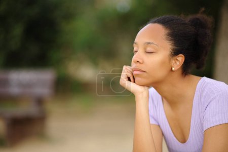 Téléchargez les photos : Femme noire esprit relaxant assis seul dans un parc - en image libre de droit