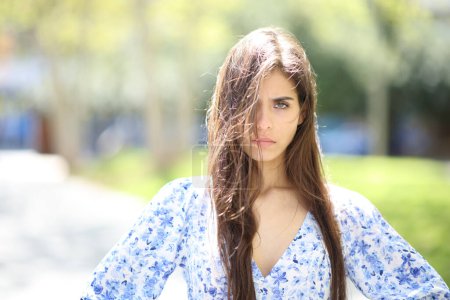 Photo for Angry woman with tousled hair a windy day looking at camera in the street - Royalty Free Image