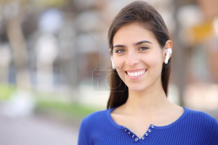 Photo for Happy woman with earphone standing and posing looking at camera in the street - Royalty Free Image