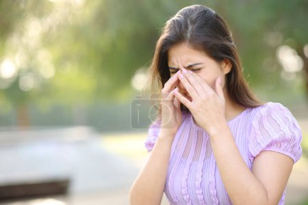 Foto de Mujer alérgica rascarse los ojos en verano en un parque - Imagen libre de derechos
