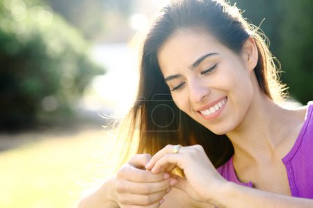 Photo for Happy fiancee looking at engagement ring in a park - Royalty Free Image