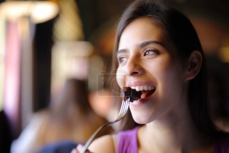 Foto de Mujer feliz comiendo carne usando tenedor en un restaurante - Imagen libre de derechos