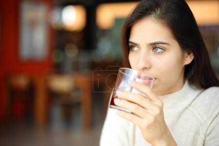 Photo for Restaurant customer drinking refreshment looking away - Royalty Free Image