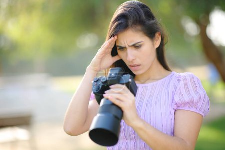 Photo for Worried photographer checking result on camera in a park - Royalty Free Image
