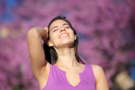 Photo for Happy woman smiling and touching hair in a violet park - Royalty Free Image
