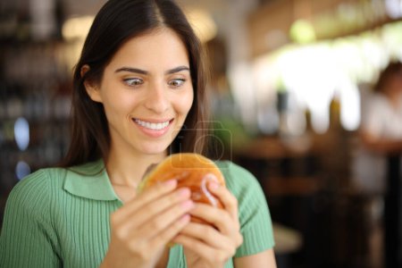Foto de Glutton mujer mirando hamburguesa en un bar interior - Imagen libre de derechos