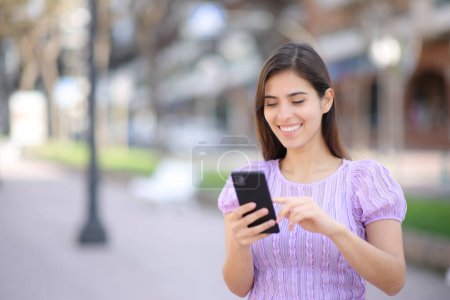 Foto de Persona feliz usando el teléfono celular caminando en la calle - Imagen libre de derechos