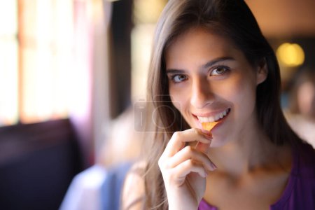 Foto de Mujer feliz en un restaurante comiendo papas fritas y mirándote - Imagen libre de derechos