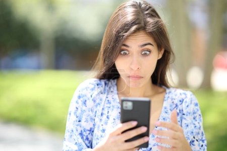 Foto de Vista frontal de una mujer perpleja revisando el teléfono en la calle - Imagen libre de derechos