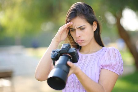 Worried photographer checking photoshoot result on camera in a park