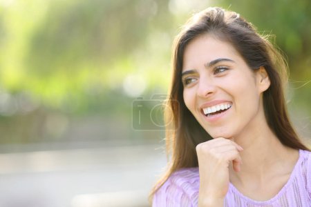 Foto de Mujer feliz con sonrisa perfecta mirando hacia otro lado en un parque - Imagen libre de derechos