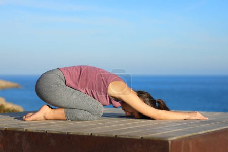 Téléchargez les photos : Profil d'une femme faisant du yoga sur la plage - en image libre de droit