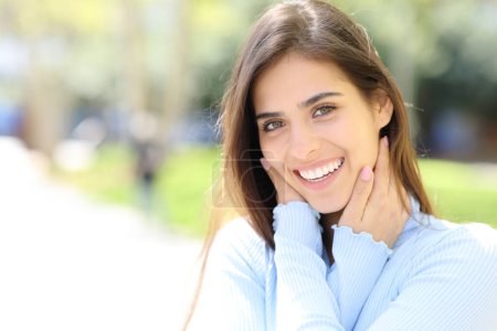Piękna kobieta z białymi zębami uśmiechnięta patrząc w kamerę na ulicy