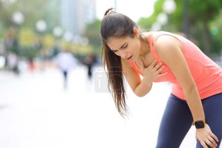 Photo for Exhausted runner touching chest breathing in the street - Royalty Free Image