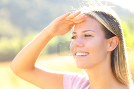 Photo for Happy woman with hand on forehead protects from sun in nature - Royalty Free Image