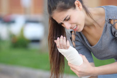 Photo for Woman suffering with bandaged sprained wrist in the street - Royalty Free Image
