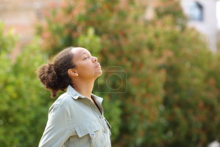 Photo for Profile of black woman meditating breathing fresh air in a park - Royalty Free Image