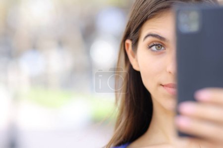 Photo for Front view close up portrait of a surprised woman checking cell phone in the street - Royalty Free Image