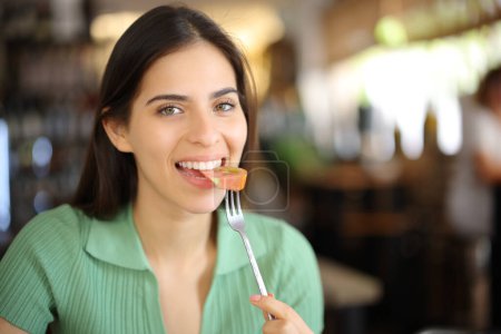 Foto de Cliente feliz restaurante comiendo tomate mirando la cámara - Imagen libre de derechos
