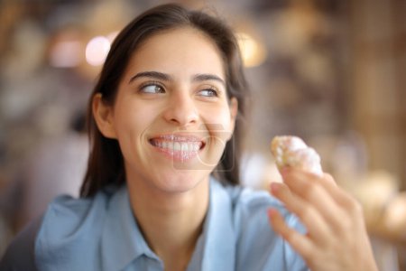 Téléchargez les photos : Heureux client restaurant manger croissant avec des lèvres sales regardant loin - en image libre de droit