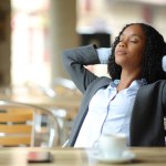 Black busineswoman resting sitting in a coffee shop terrace