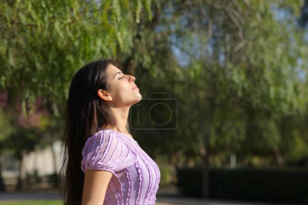 Téléchargez les photos : Profil d'une femme détendue dans un parc respirant l'air frais - en image libre de droit
