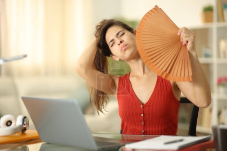 Photo for Stressed student fanning at home suffering heat stroke - Royalty Free Image