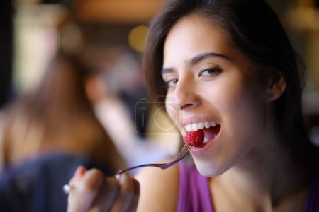 Téléchargez les photos : Femme heureuse mordant mûre dans un bar intérieur - en image libre de droit