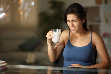 Téléchargez les photos : Femme souffrant d'intolérance au lactose après avoir bu du lait dans la nuit à la maison - en image libre de droit