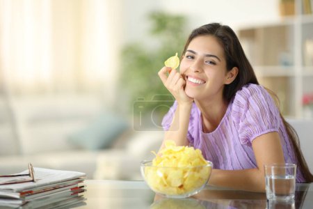 Foto de Mujer feliz posando con patatas fritas mirándote en casa - Imagen libre de derechos