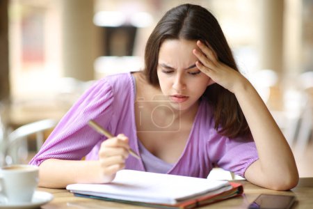 Photo for Stressed student studying hard memorizing notes in a bar terrace - Royalty Free Image