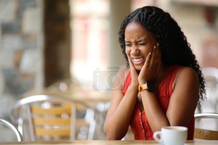 Black woman suffering tmj and complaining in a restaurant terrace