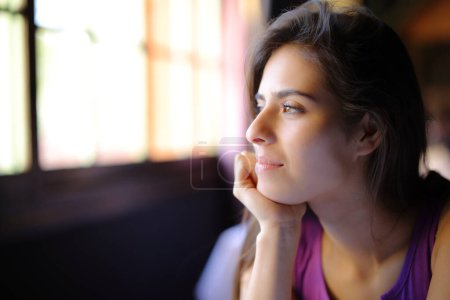 Foto de Mujer satisfecha mira a través de una ventana en casa - Imagen libre de derechos