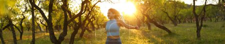 Photo for Banner of a front view of a happy woman running towards camera at sunset in a field - Royalty Free Image