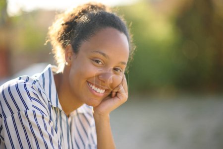 Foto de Mujer negra feliz mirándote sentada en la calle - Imagen libre de derechos