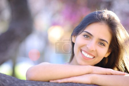 Téléchargez les photos : Portrait d'une femme heureuse avec un sourire blanc dans un parc - en image libre de droit