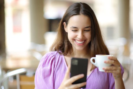Foto de Mujer feliz usando el teléfono bebiendo café sentado en una terraza del restaurante - Imagen libre de derechos