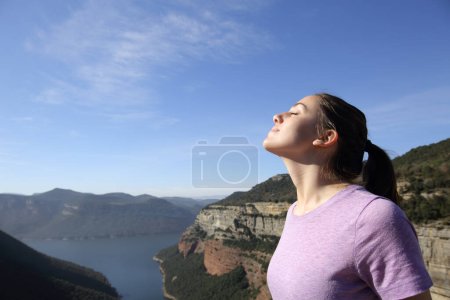 Foto de Mujer respirando aire fresco en un acantilado un día soleado en la montaña - Imagen libre de derechos