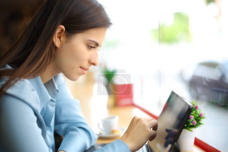 Téléchargez les photos : Portrait latéral d'une femme dans un café en utilisant la tablette seule - en image libre de droit