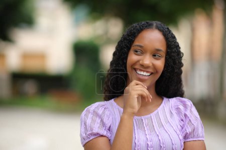 Photo for Front view portrait of a happy black woman thinking looking at side in the street - Royalty Free Image