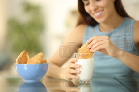 Photo for Happy woman dipping croissant in milk glass at home - Royalty Free Image