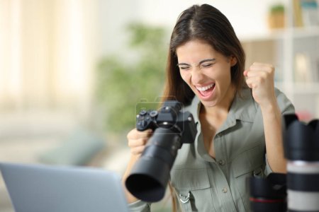 Photo for Excited photographer at home celebrating good result on camera - Royalty Free Image