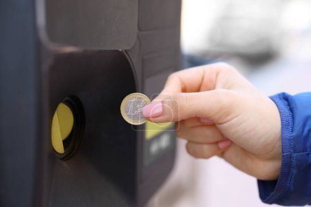 Téléchargez les photos : Gros plan portrait d'une femme main à l'aide de pièce de monnaie pour payer le parcmètre - en image libre de droit