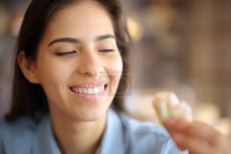 Téléchargez les photos : Femme heureuse mangeant un croissant sucré aux lèvres sales dans un restaurant - en image libre de droit