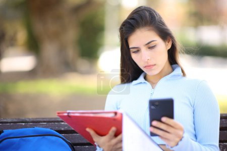 Photo for Student checking smart phone sitting in a park - Royalty Free Image