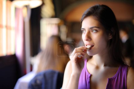 Foto de Hermoso cliente comiendo pan en el interior de un restaurante - Imagen libre de derechos