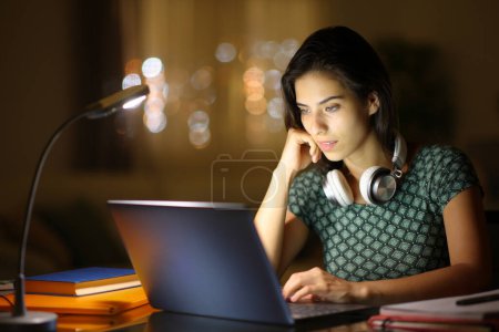 Téléchargez les photos : Étudiant dans la nuit e-learning en utilisant un ordinateur portable à la maison - en image libre de droit
