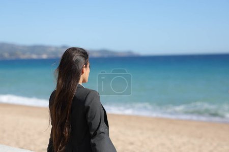 Foto de Ejecutivo único relajante contemplando el océano sentado en la playa - Imagen libre de derechos