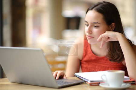 Téléchargez les photos : E-learning étudiant avec ordinateur portable dans une terrasse de café - en image libre de droit